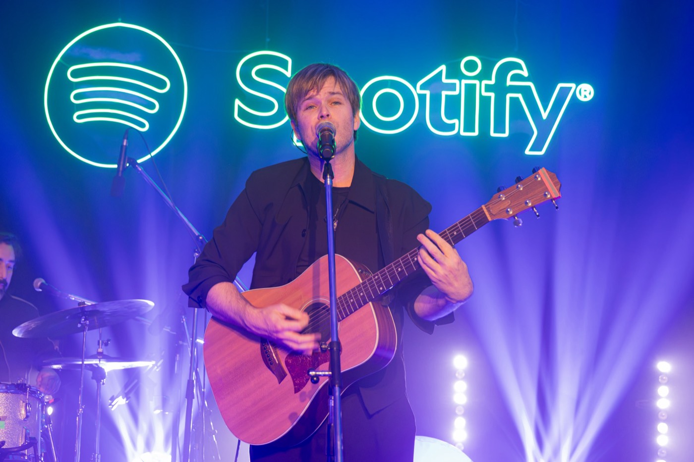 Benja Amadeo cantando con guitarra frente al logo de Spotify
